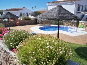 a swimming pool with an umbrella and some flowers at El Capistrano Sur in Nerja