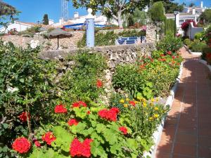 a garden with red and yellow flowers and a stone wall at El Capistrano Sur in Nerja