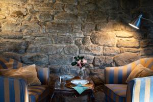 una mesa en una habitación con 2 sillas y una pared de piedra en Castello di Volpaia en Radda in Chianti