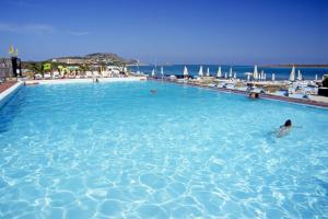 a person swimming in a large swimming pool at UNAHOTELS Club Hotel Ancora in Stintino