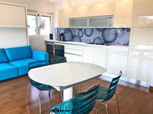 a kitchen with a white table and chairs and a blue couch at Roggia Apartments by Quokka 360 - a stone's throw from Ciani Park in Lugano