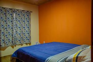 a bedroom with a blue bed and a window at Chalé vista da mata in Visconde De Maua