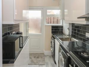 a white kitchen with a sink and a washer and dryer at Park Road in Blackpool