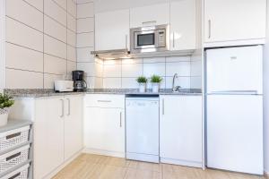 una cocina blanca con armarios y electrodomésticos blancos en Apart-rent Apartament Av Rhode 1º 2009, en Roses