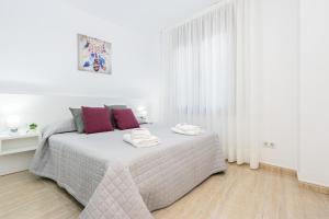 um quarto branco com uma cama com almofadas roxas em Apart-rent Apartament Av Rhode 1º 2009 em Roses