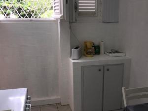 a white kitchen with a counter and a window at Le Belleplaine in Le Gosier