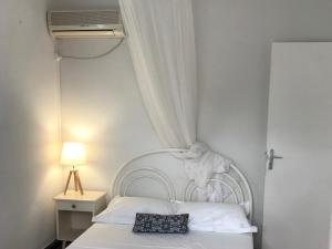 a bedroom with a white bed with a pillow on it at Le Belleplaine in Le Gosier