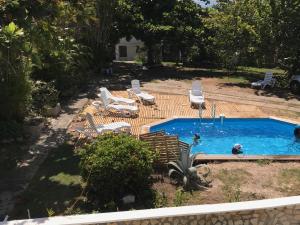 a backyard with a pool with chairs and a person in it at Le Belleplaine in Le Gosier