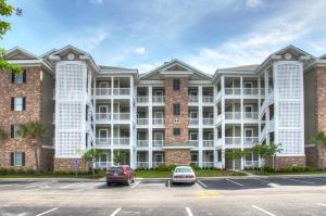 a large apartment building with cars parked in a parking lot at Magnolia Pointe by Palmetto Vacations in Myrtle Beach