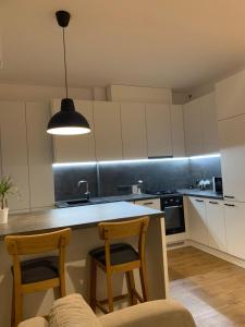 a kitchen with white cabinets and two chairs and a counter at Staadioni apartment in Tartu