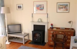 a living room with a fireplace and a tv at The Boathouse for two, St Davids, Garage Parking in St. Davids