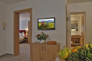 a living room with a tv on the wall and people riding bikes at Appartement Schörghofer in Filzmoos