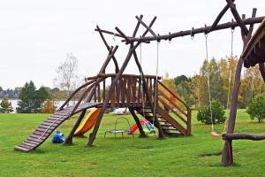 a playground with a slide and swings in a park at Sodyba Pas Drambliuka in Svėdasai