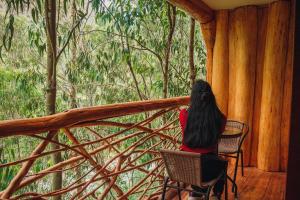 聖特雷莎區的住宿－蓋丘亞生態山林小屋，坐在门廊椅子上的女人