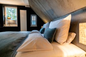 1 dormitorio con 1 cama grande con almohadas blancas en country-suites by verdino LIVING - Apartments & Suites, en Braunlage