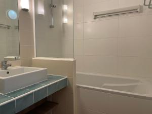 uma casa de banho branca com um lavatório e uma banheira em appartement vue mer 50m de la plage, WIFI gratuit em Perros-Guirec