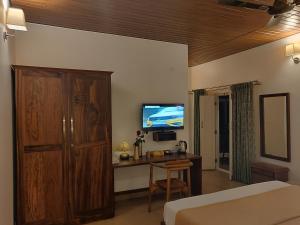a bedroom with a bed and a desk with a television at Elegant holiday homes Coorg in Madikeri