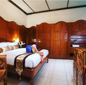 a bedroom with a large bed and wooden cabinets at Raintree Boutique Villa & Gallery in Yogyakarta