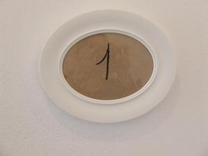 eine Uhr auf einem weißen Schild an der Wand in der Unterkunft Bilocale Papavero, Magnolia o Girasole in San Felice del Benaco