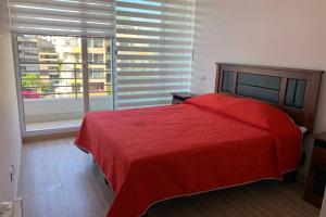 a bedroom with a red bed and a large window at Arriendo departamento excelente ubicación por día in Viña del Mar