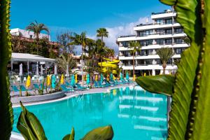 una piscina con sillas y un hotel en el fondo en Spring Hotel Bitácora, en Playa de las Américas