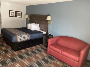 um quarto de hotel com uma cama e uma cadeira vermelha em Lakeside Inn em Guntersville