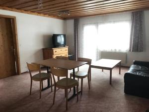 a living room with a table and chairs and a television at Hotel Alpina in Unterwasser