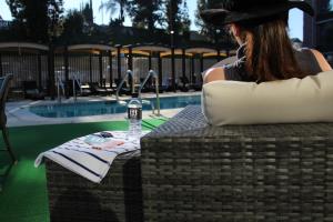 Eine Frau mit einem Hut, die auf einem Tisch neben einem Pool sitzt. in der Unterkunft The Hills Hotel, an IHG Hotel in Laguna Hills