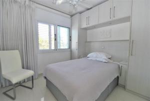 a white bedroom with a bed and a chair at Savveli by the sea in Paphos City