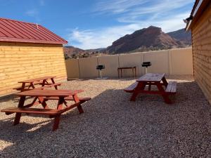 two picnic tables sitting next to a building with a mountain at Red Canyon Cabins in Kanab