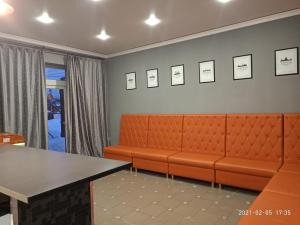 a waiting room with an orange couch and a table at Дом с часами на Вокзальной 85 in Domodedovo