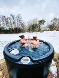 two women sitting in a jacuzzi in a snow covered at The island life texel met jacuzzi in De Koog