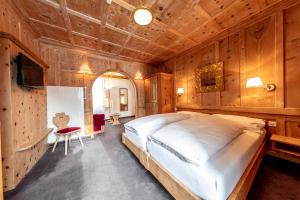 a bedroom with a large bed in a room with wooden walls at Hotel Filli in Scuol