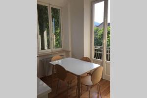 a white table and chairs in a room with windows at Luminoso appartamento in Villa a Stresa in Stresa