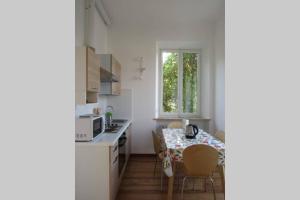 una cucina con tavolo, sedie e finestra di Luminoso appartamento in Villa a Stresa a Stresa