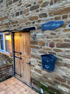 ein Steingebäude mit einer Tür und einem Schild darauf in der Unterkunft Holcot Cottage 