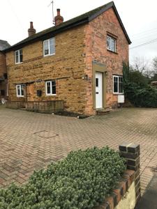 a brick house with a brick driveway in front of it at Holcot Cottage 