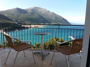 einen Balkon mit einem Tisch und Stühlen sowie Blick auf das Wasser in der Unterkunft Hotel Oceanis in Póros