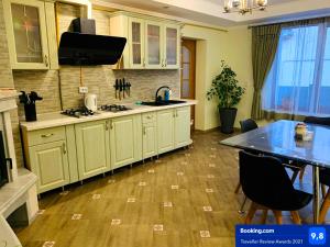 uma cozinha com armários brancos e piso em madeira em Зелений Дім - ViriDi House em Morshin