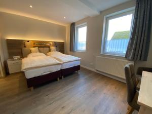 ein Schlafzimmer mit einem großen Bett und zwei Fenstern in der Unterkunft Ferienwohnungen Zum Lindenwirt in Weißehütte
