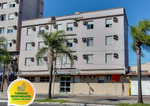 um grande edifício branco com palmeiras em frente em Hotel Expressinho Aeroporto em Porto Alegre