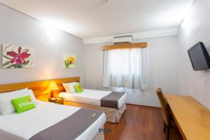 a hotel room with two beds and a television at VOA Express Inn Hotel Orquídea in Várzea Paulista
