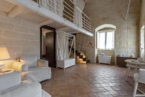 una sala de estar con muebles blancos y una pared de piedra. en Le Dimore Dell' Idris, en Matera