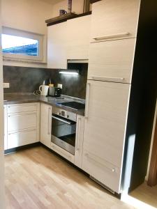 Attalens的住宿－Cozy 2.5 Apartment with Swimmingpool，厨房配有白色橱柜和炉灶烤箱。