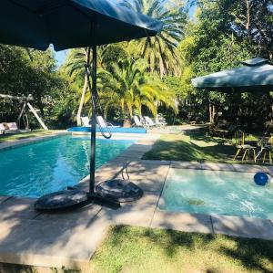 a pool with an umbrella and chairs and a table at Chacra La Escondida in Colonia del Sacramento