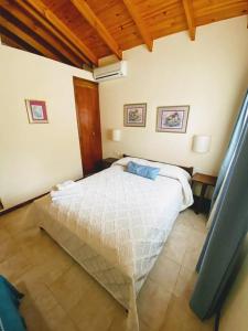 een slaapkamer met een wit bed in een kamer bij Lo de la Omi in Villa General Belgrano