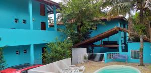 ein blaues Gebäude mit einem Tisch und Stühlen davor in der Unterkunft Atlântico in Maresias