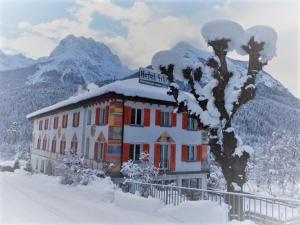 un bâtiment recouvert de neige avec des montagnes en arrière-plan dans l'établissement Hotel Filli, à Scuol