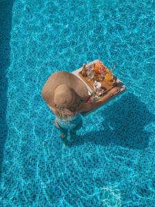 a person in a straw hat sitting in a swimming pool at Agava Lux Rooms&Pool in Split