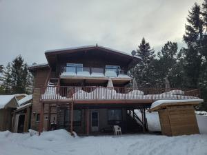 une cabane en rondins avec une terrasse dans la neige dans l'établissement Whispering Pines Suite at The Bowering Lodge, à Blue Mountains